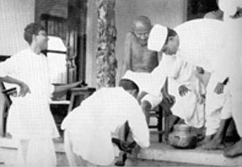 A barber extracting thorn from Gandhi's foot, Wardha, August 1939